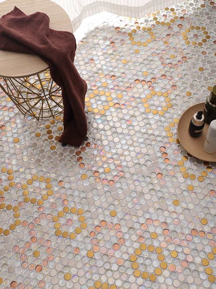 Round glass and metal mosaic bathroom floor with a simple stool and towel