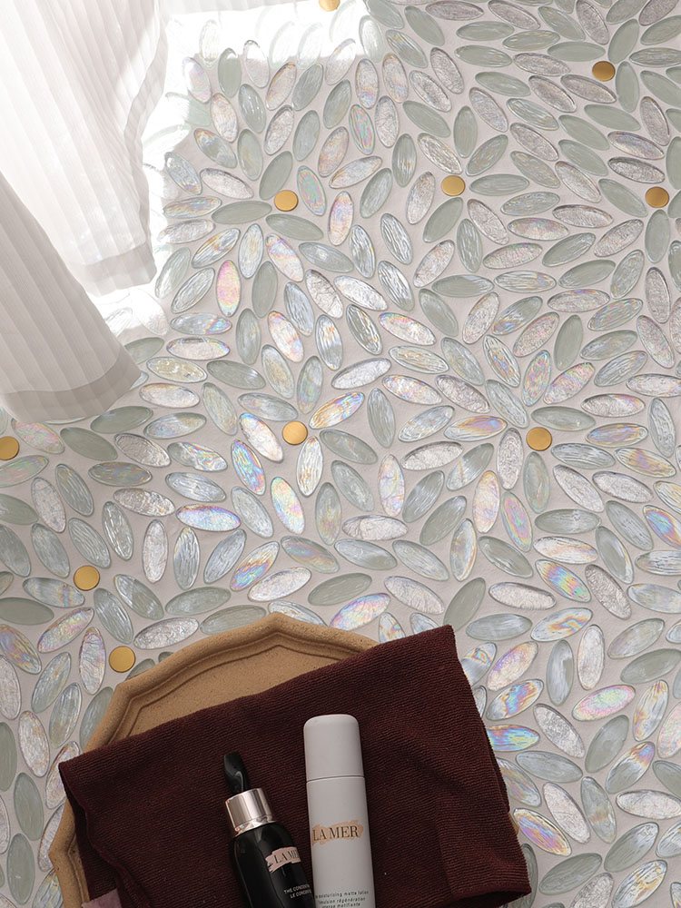 The unique blend of oval and round glass mosaic tiles adds elegance to the bedroom floor, accompanied by soft white curtains and neatly arranged skincare products