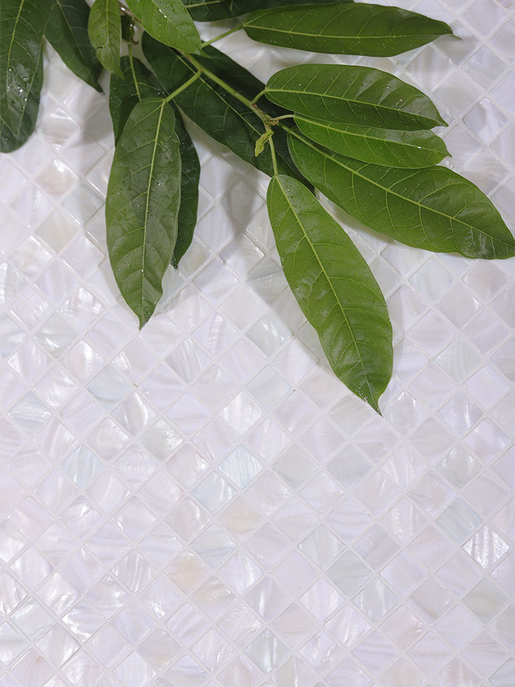 The white natural shell mosaic tiles exude a soft, organic elegance, enhanced by the refreshing presence of green leaves for a harmonious, nature-inspired design