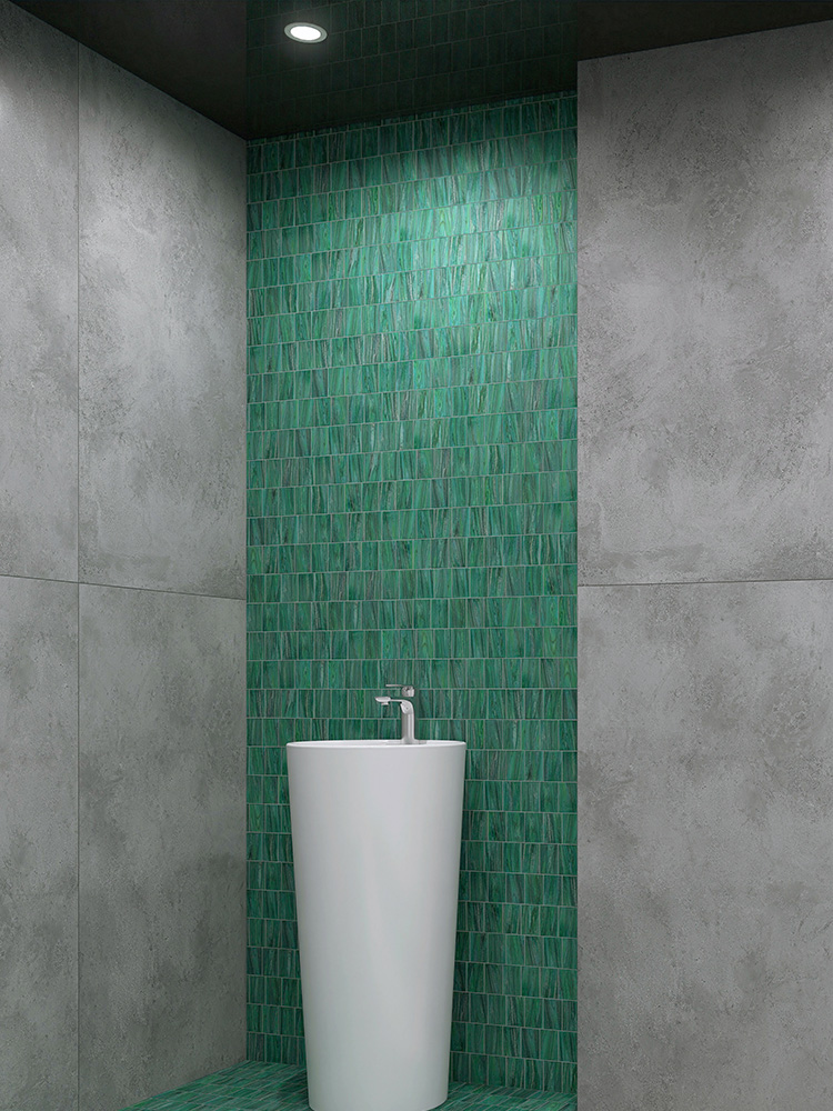 The green mosaic tiles on the bathroom walls create a refreshing look, beautifully complemented by gray floor tiles and a sleek white ceramic sink for a modern, balanced design.