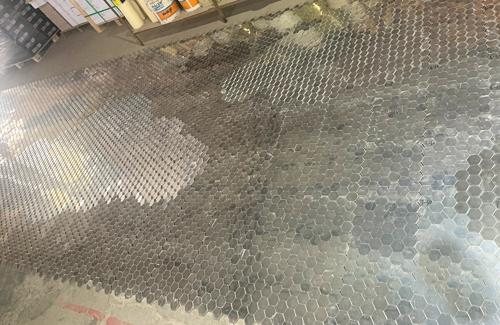 Adjusting hexagonal mosaic tiles during production.