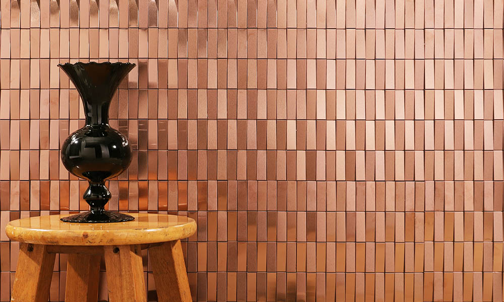 Rose gold 3D stainless steel mosaic tiles on the wall with a black vase in front
