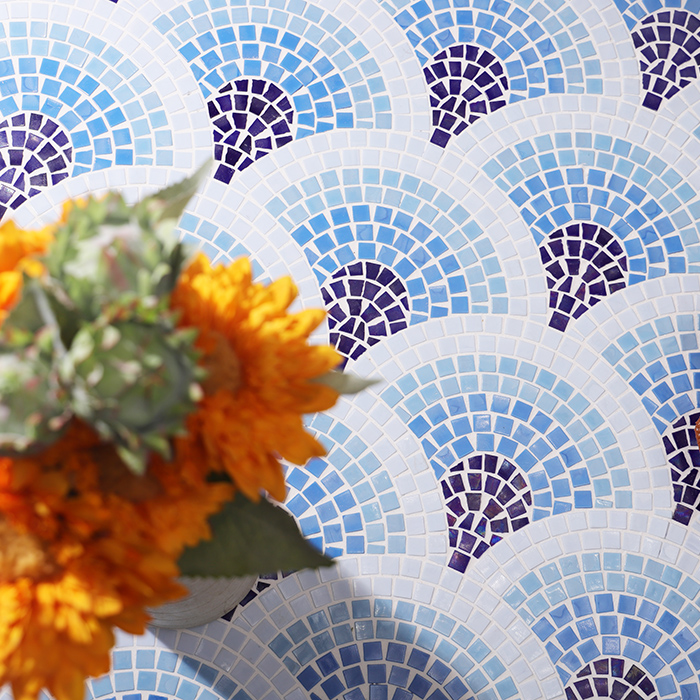 Blue hand-cut fish scale mosaic tiles on the floor with a bouquet of flowers beside them.