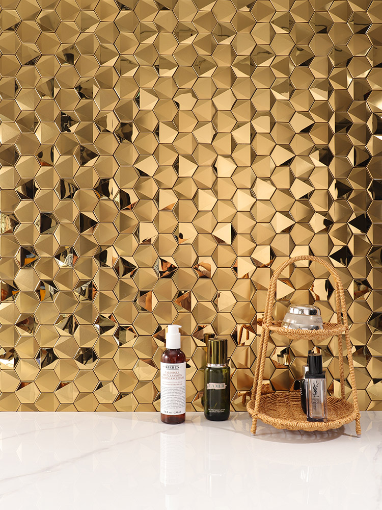 Gold hexagonal 3D mosaic on sink wall.