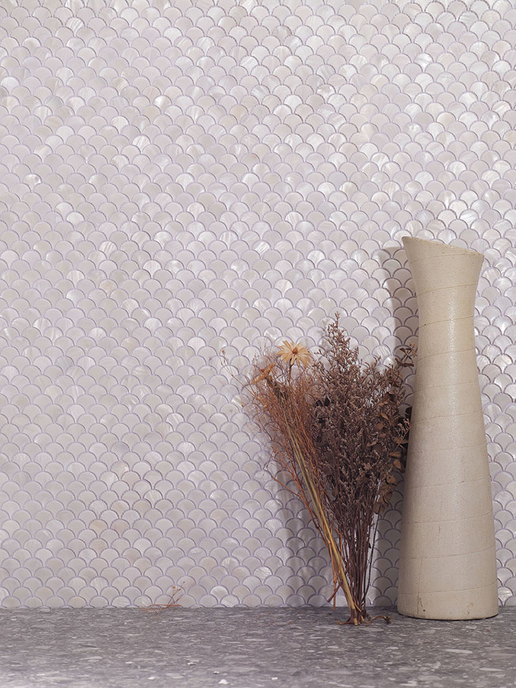 Fan-shaped white shell mosaic tiles on the wall with gray floor tiles and a bouquet