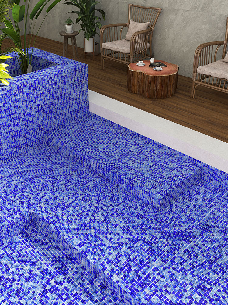 Blue mosaic tiles in the pool with chairs by the poolside.