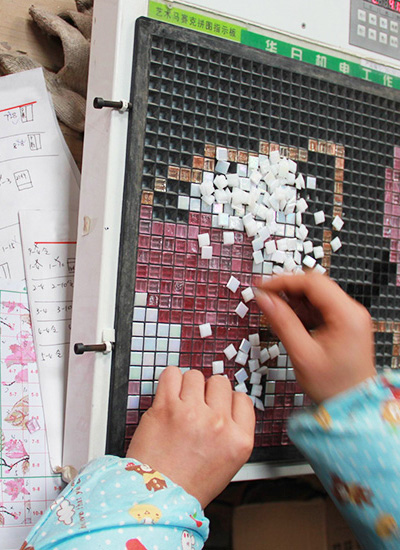 A worker creating small pieces for pixel mosaic tiles.