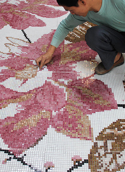 A worker inspecting finished pixel mosaic tiles.