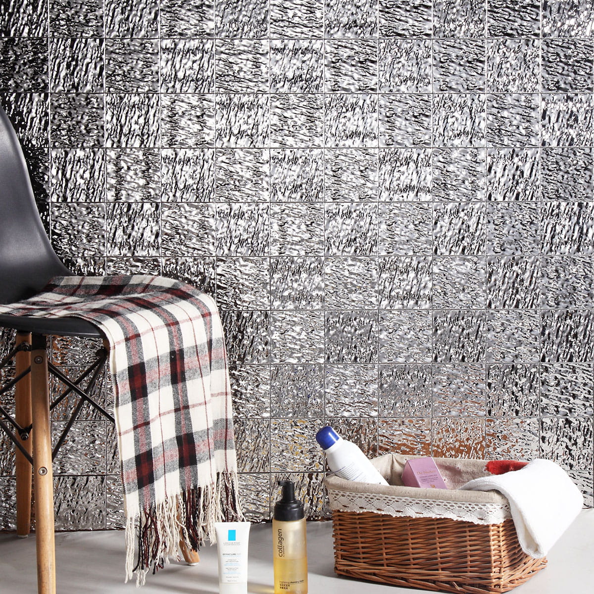 Accent wall covered in shiny silver tiles with a wave pattern behind a cozy chair setup 