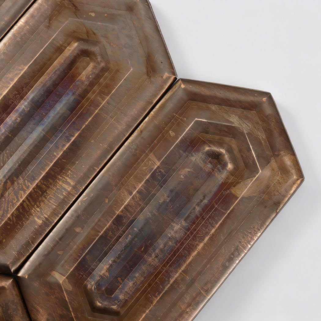 Close up of antique bronze elongated hexagon mosaic showing worn metallic texture.