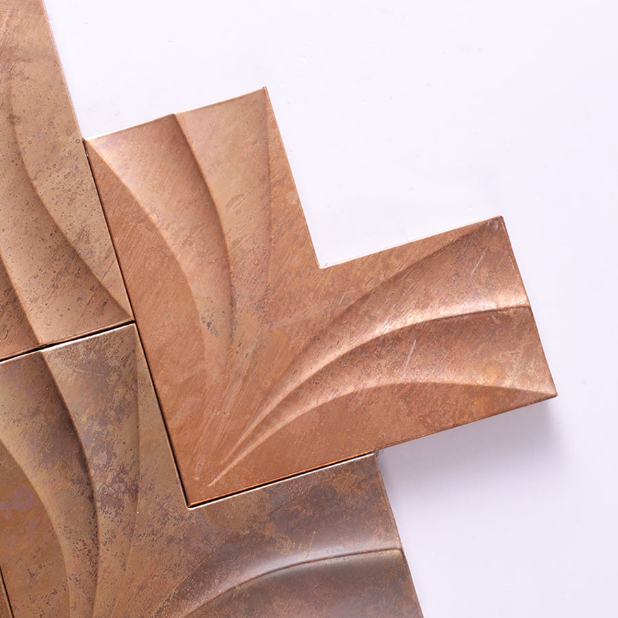 Corner close-up of antique copper leaf pattern metal mosaic tile.