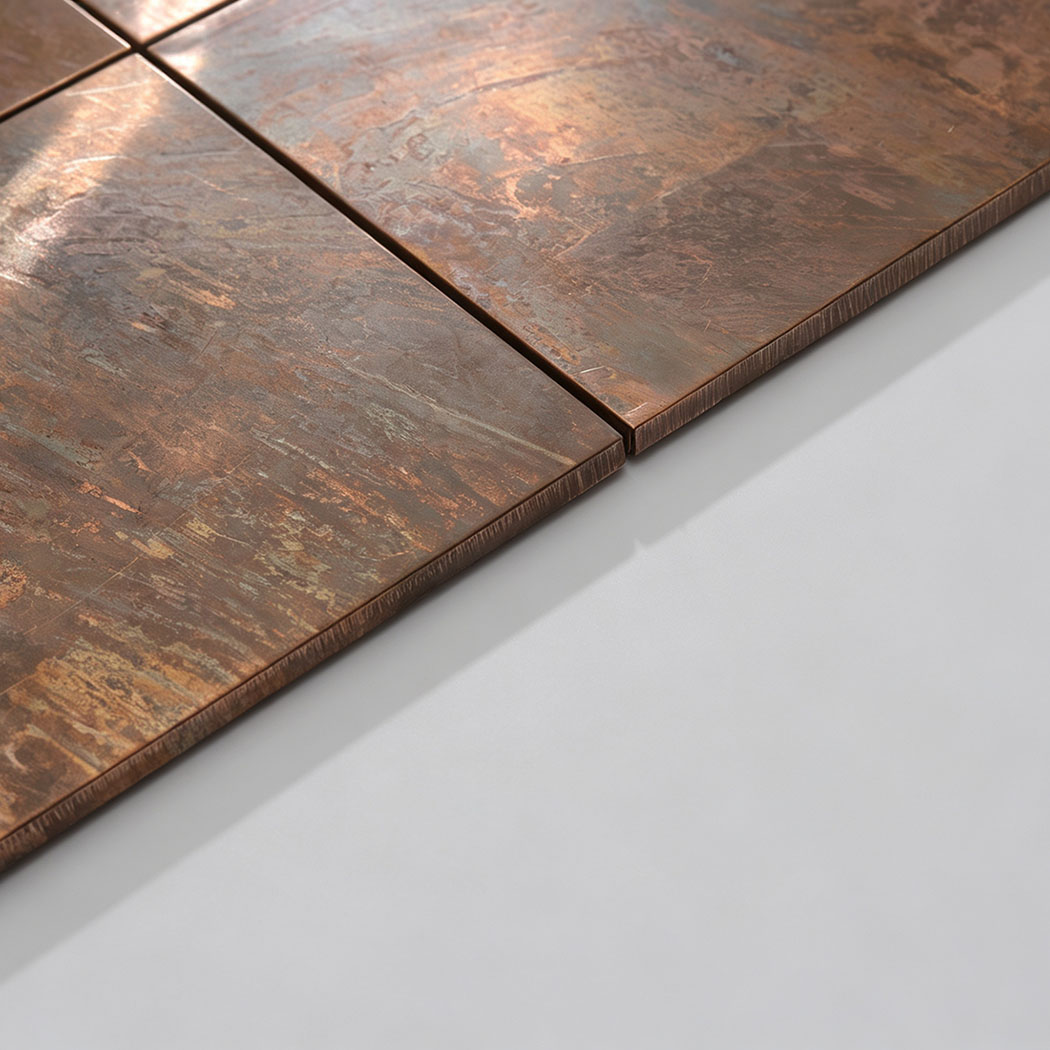 Angled view of antique copper mosaic tiles showing slim edges and metallic sheen