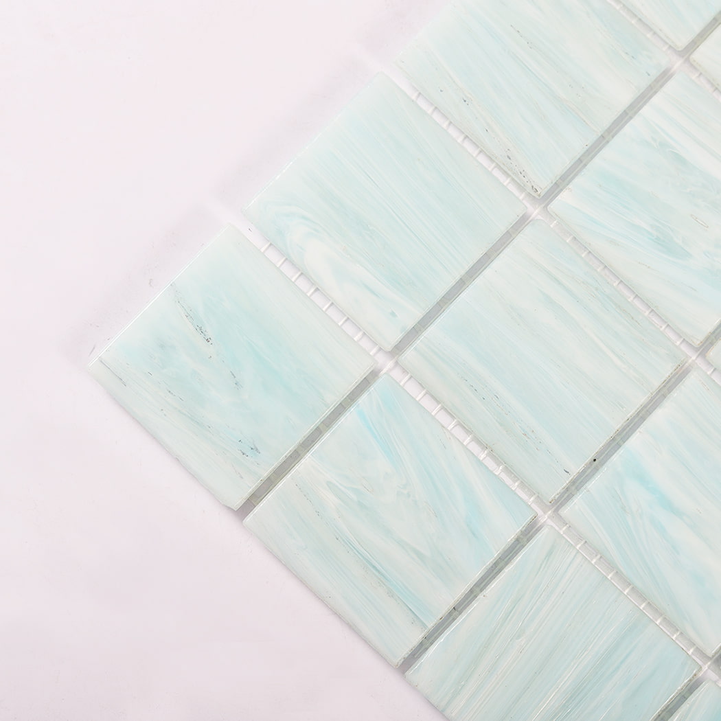Corner close up of aqua blue glass mosaic tiles showing mesh backing and grout lines