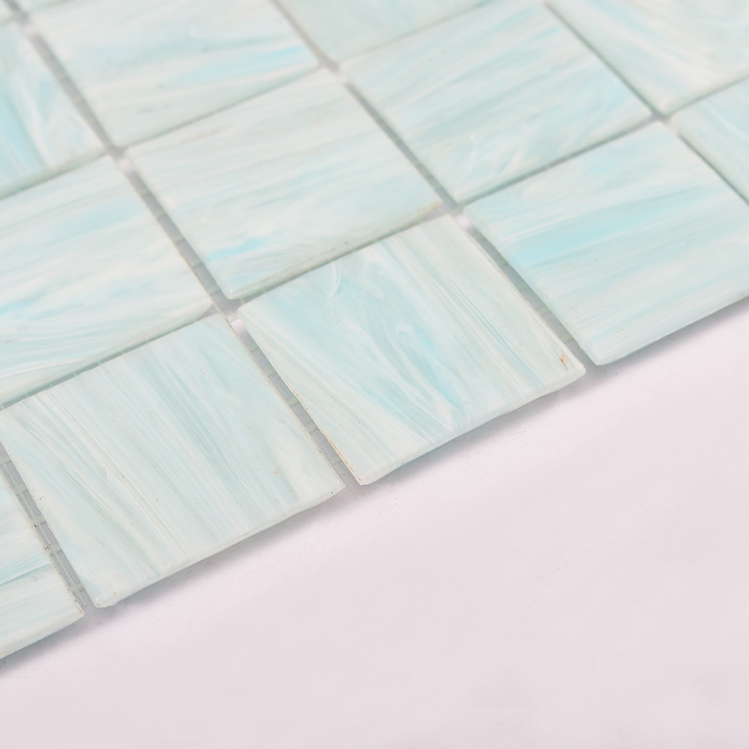 Side angle close up of aqua blue glass mosaic tiles showing tile edges and thickness