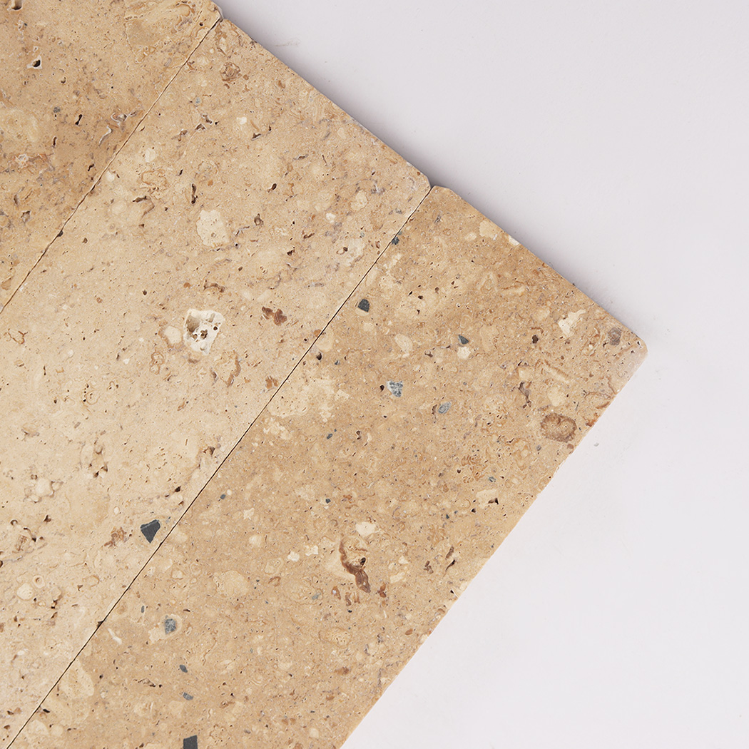 Close up of beige limestone tile corner with natural shell and stone markings