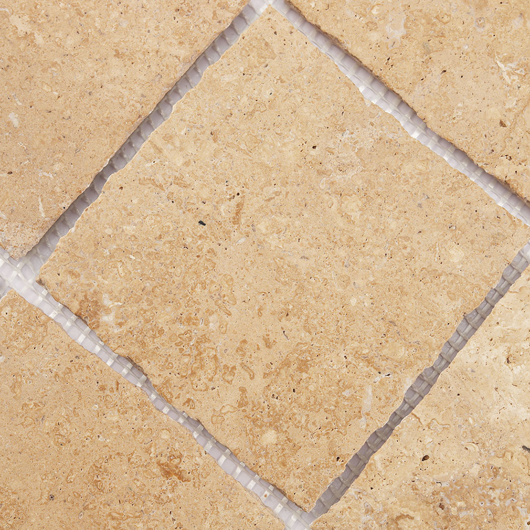 Beige square limestone tile detail showing soft stone speckles and natural variation