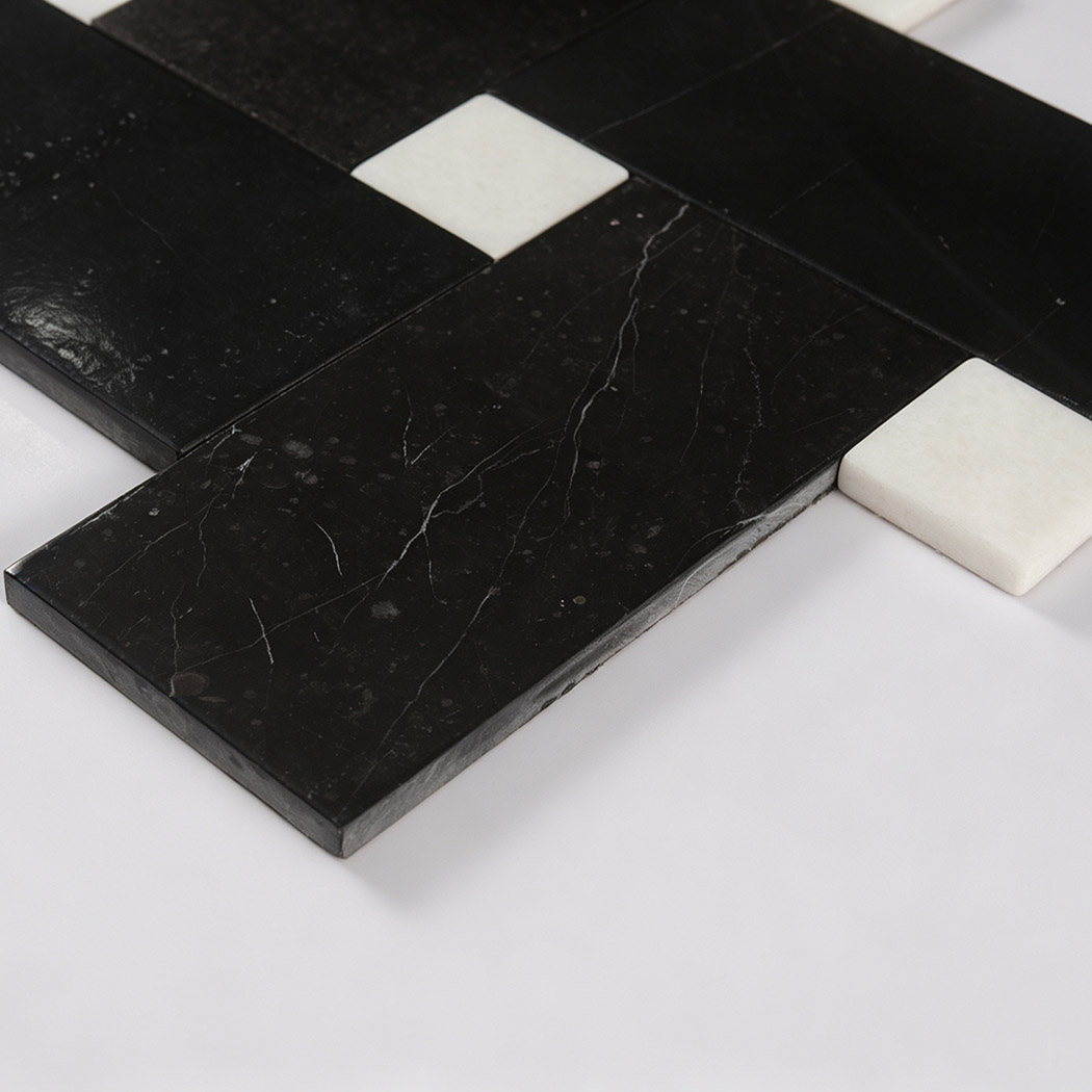 Angled close-up of black marble geometric tile with white square inserts