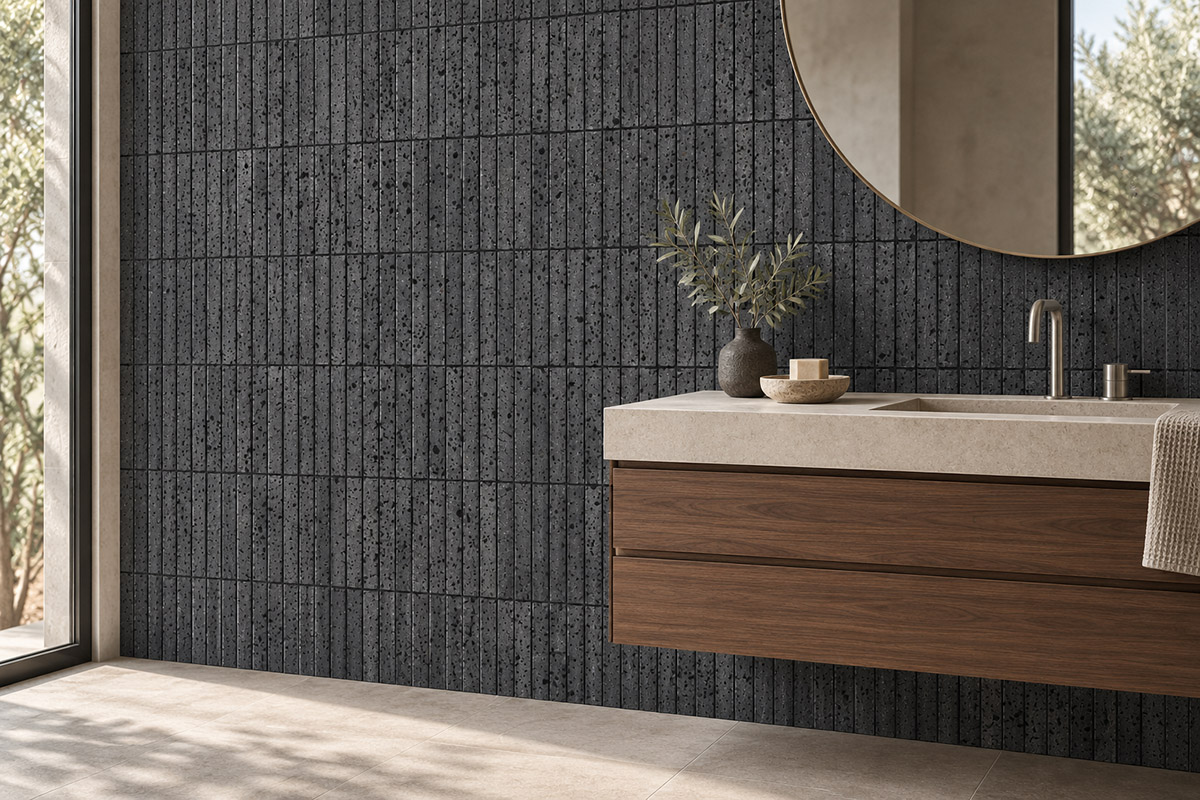 Black lava stone tiles laid vertically behind a floating wood vanity and round mirror.