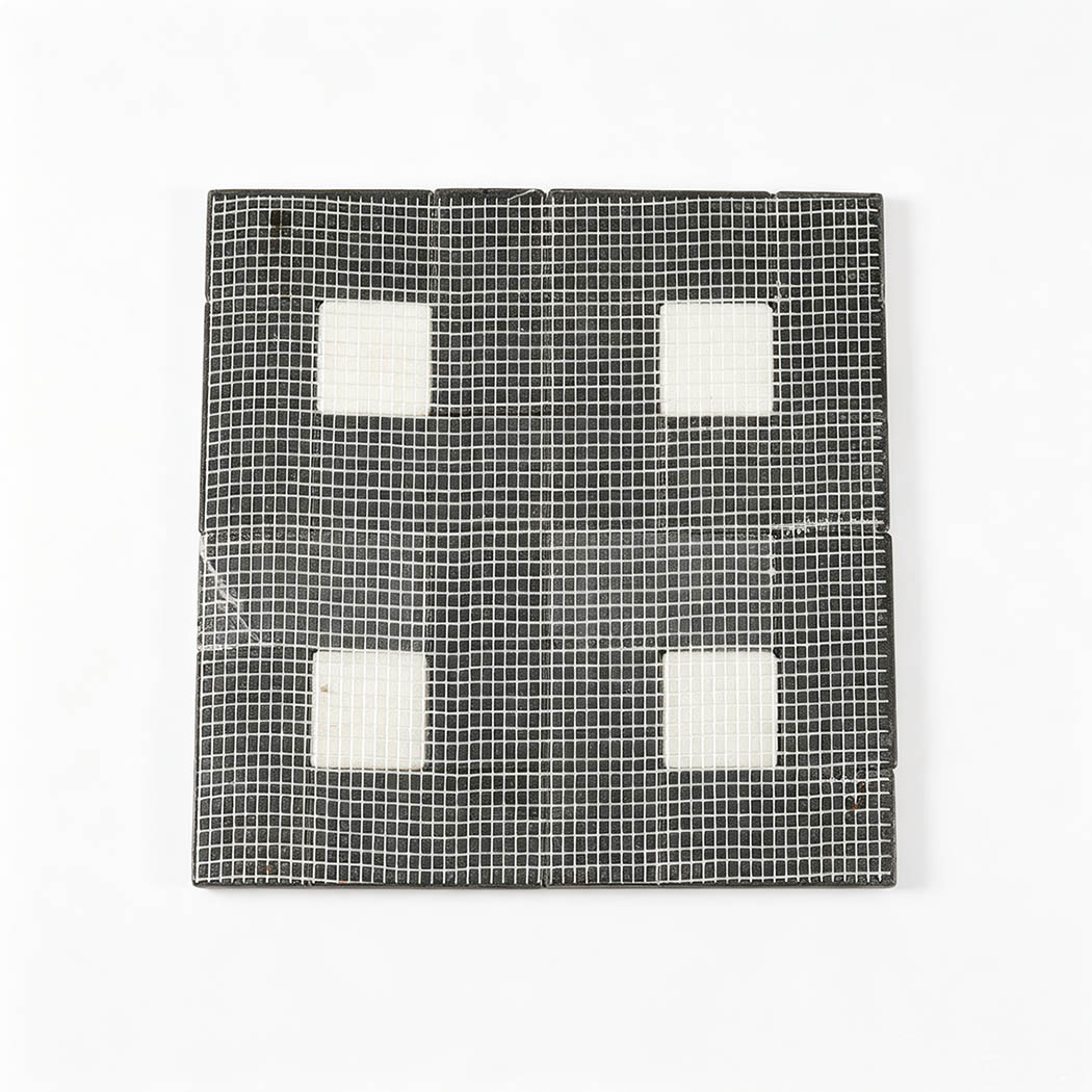 Mesh backing of black marble geometric mosaic with four white square accents