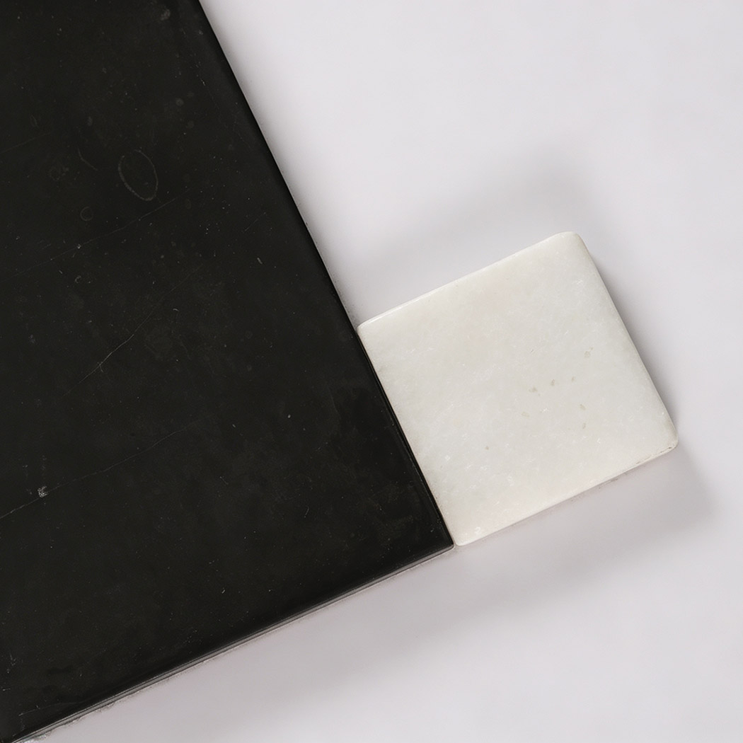 Close-up of black marble rectangle and white square tile with natural texture