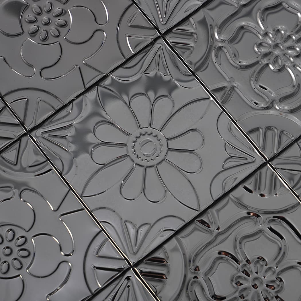 Close-up of black embossed patchwork mosaic tiles showing glossy floral and geometric motifs.