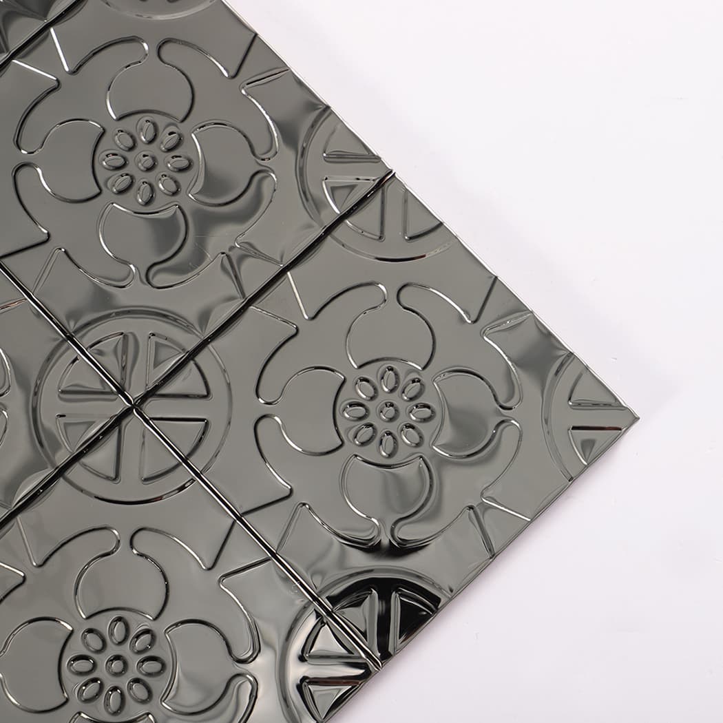 Close-up of a corner showing raised floral embossing on black metal mosaic tiles.
