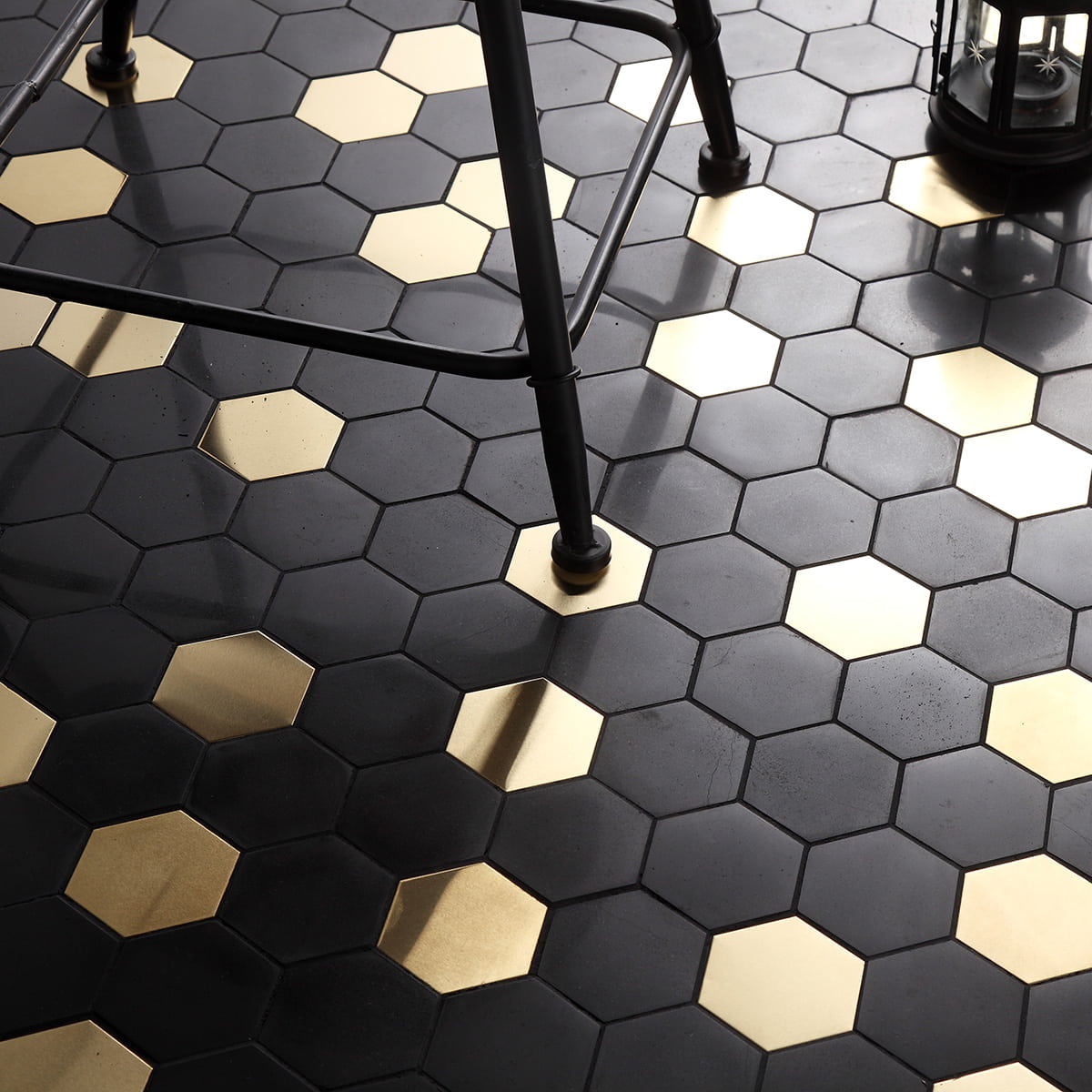 Black and gold hexagonal mosaic tiles with a chair and lantern on the floor