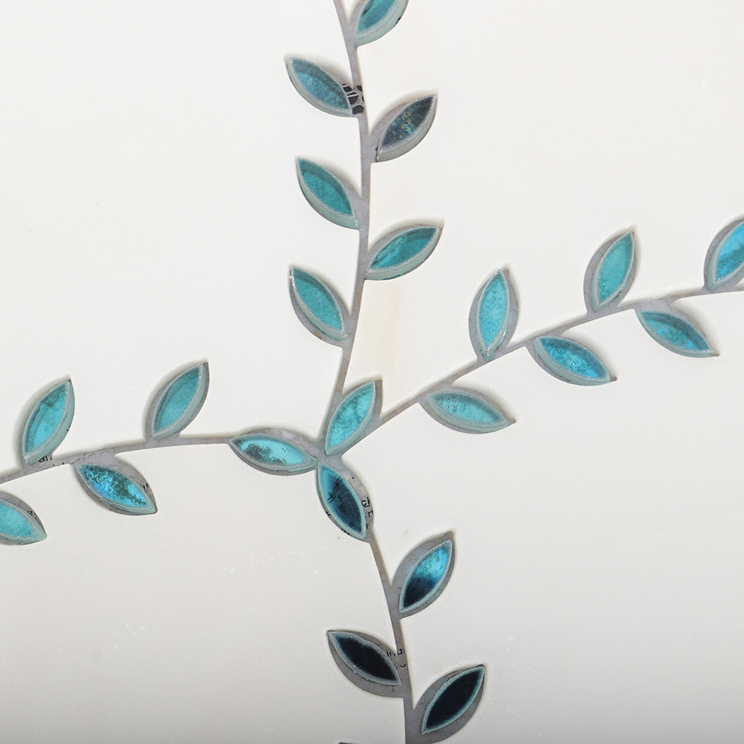 Detailed view of blue leaf pattern arranged in branch shapes on a marble tile.