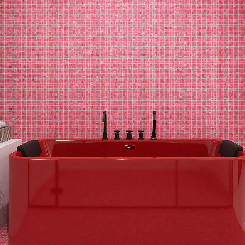 A close-up of a red freestanding bathtub set against a blush pink glass mosaic tile wall 
