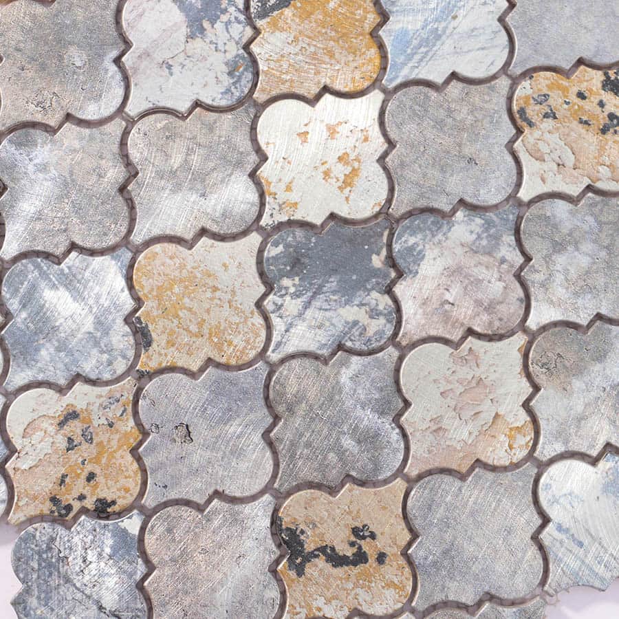 Close-up of brushed aluminum tile surface showing weathered texture and multi-tone metallic finish.