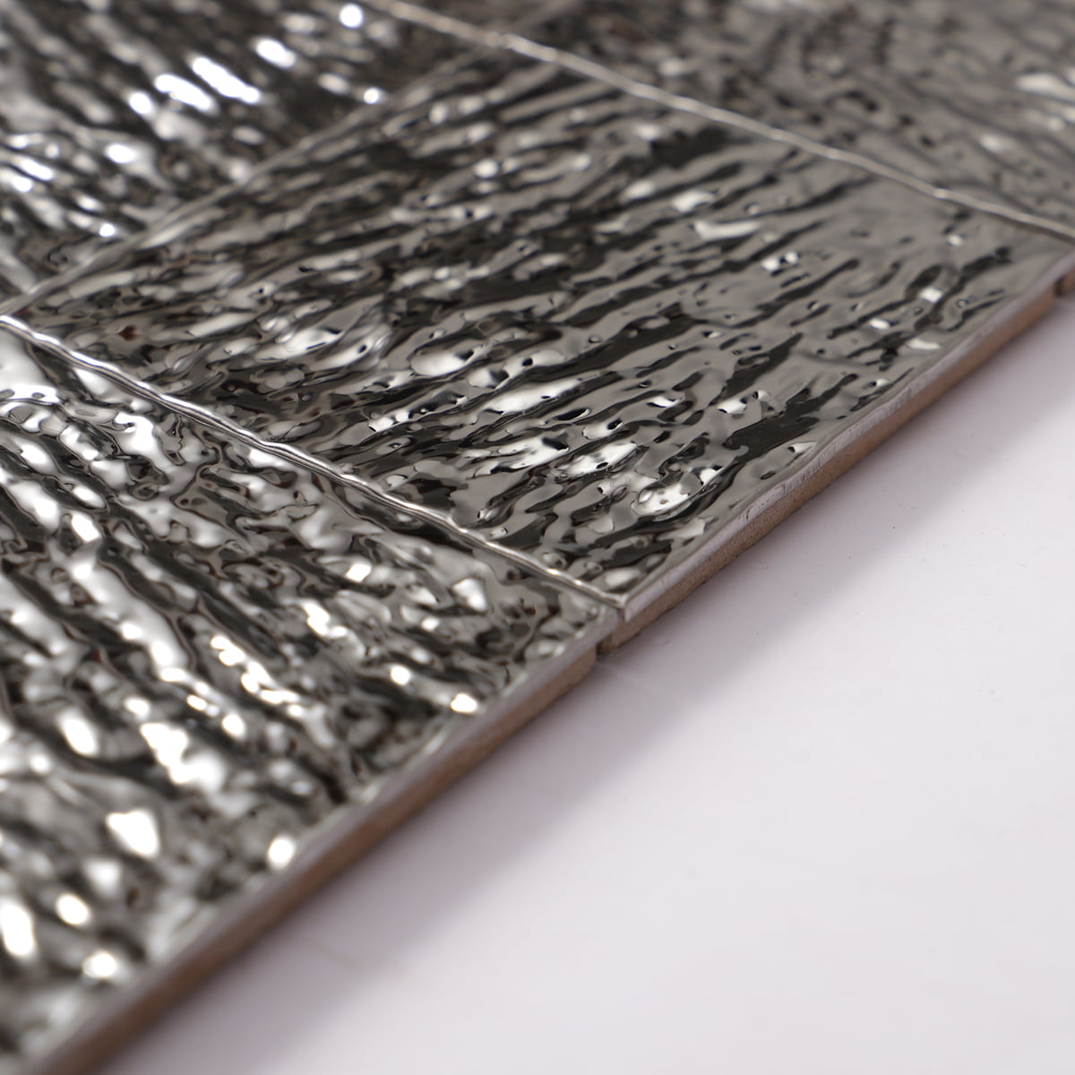 Close-up of wavy metallic silver tiles with 3D texture and smooth edges