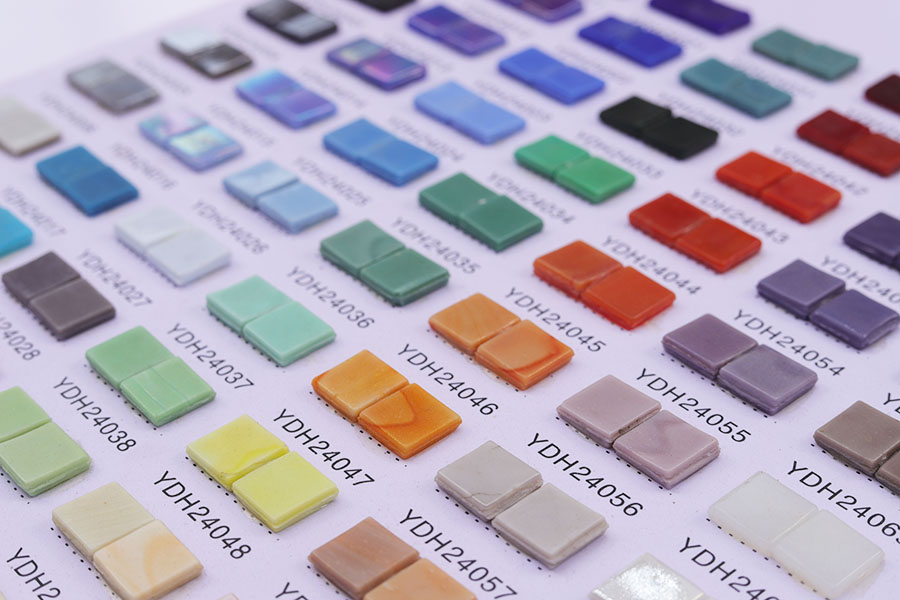 Close-up view of colorful glass mosaic tile samples with product codes