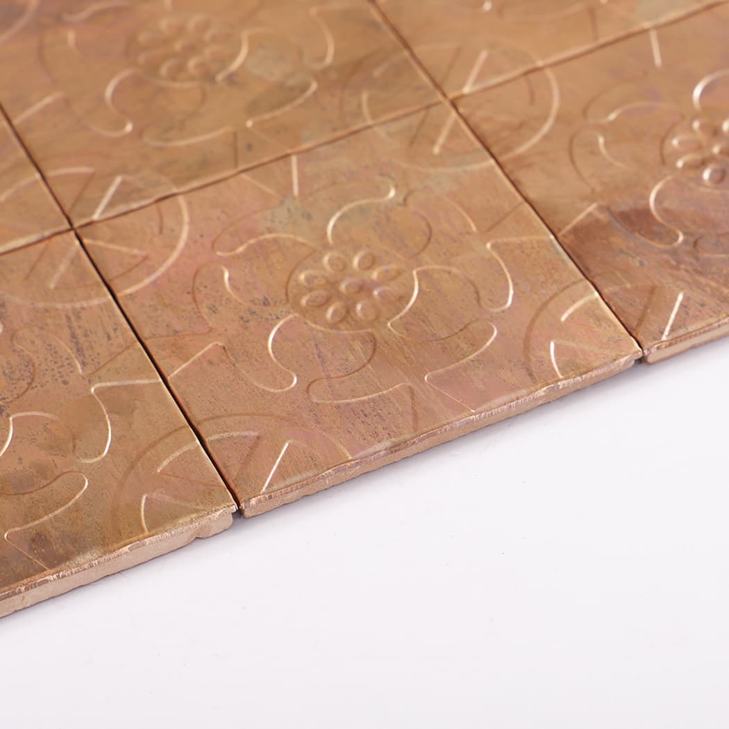 Side angle view of copper embossed mosaic tile sheet showing raised pattern and tile edges.