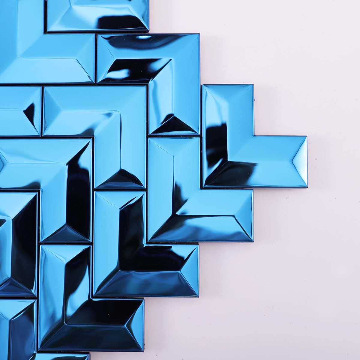 Corner close-up of glossy 3D blue stainless chevron tile