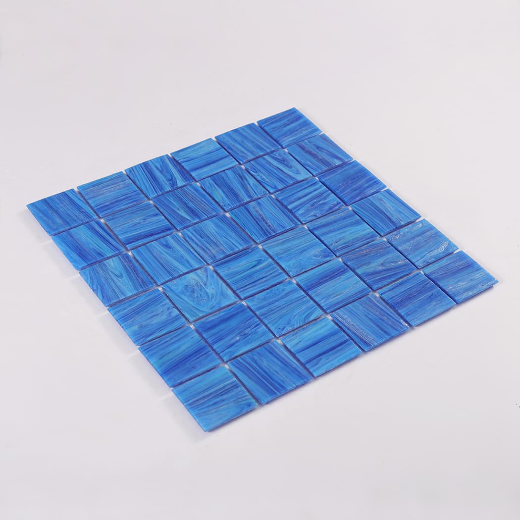 Angled product photo of dark blue glass mosaic tile sheet on white