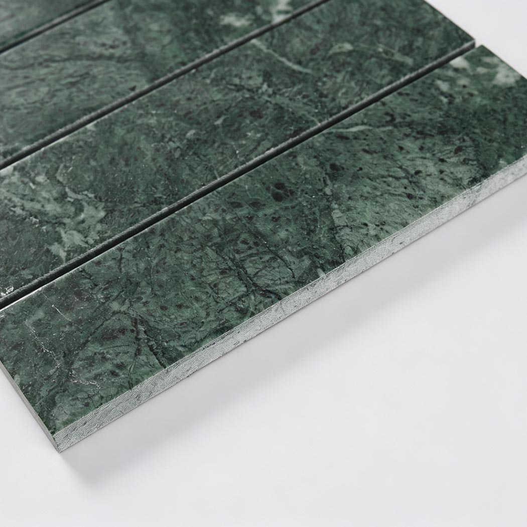 Side close-up of dark green marble strip tile showing thickness and straight edges