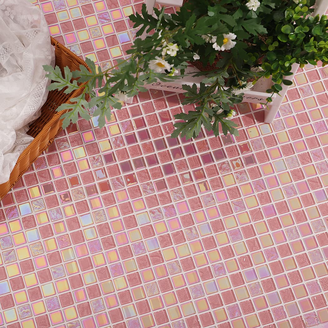 Wide angle shot of a pink glass mosaic tile surface decorated with lace and white flowers.