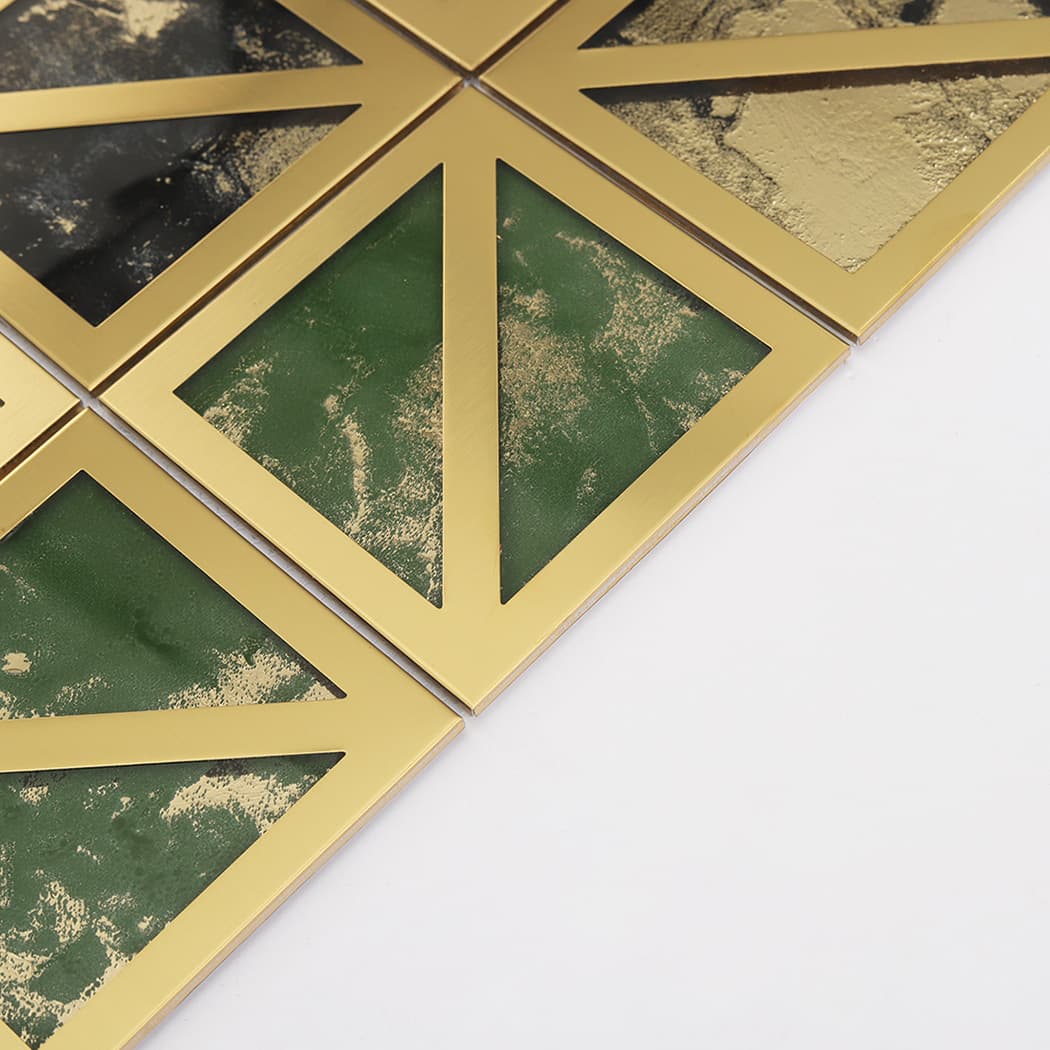 Close-up of green marble pattern mosaic tiles divided by diagonal gold metal lines.