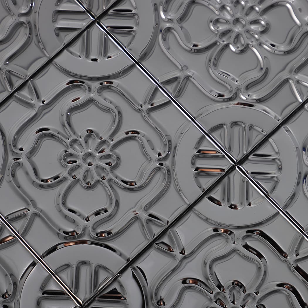 Diagonal close-up of embossed black floral metal tile pattern with glossy reflective finish.