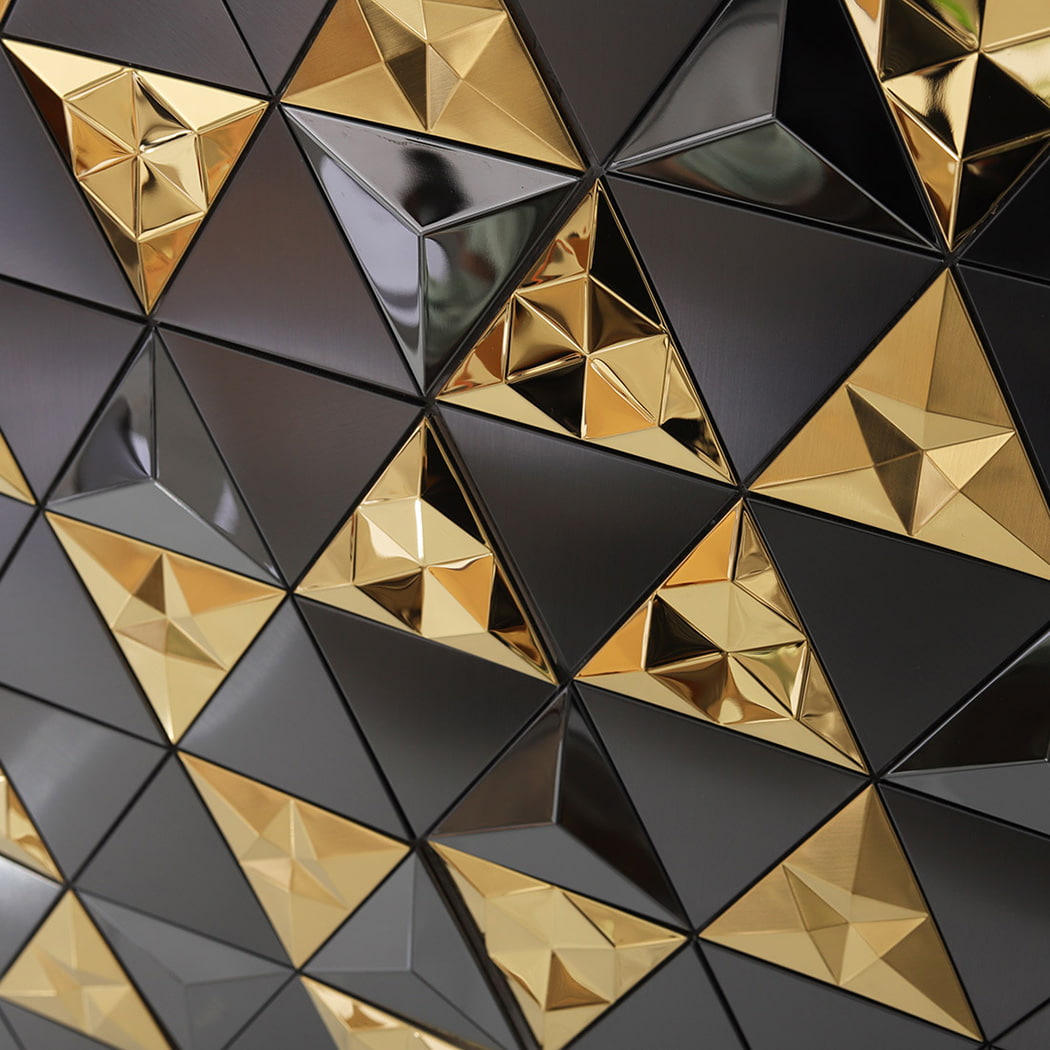 Geometric repeating pattern of 3D black and gold metal mosaic tiles on a wall.