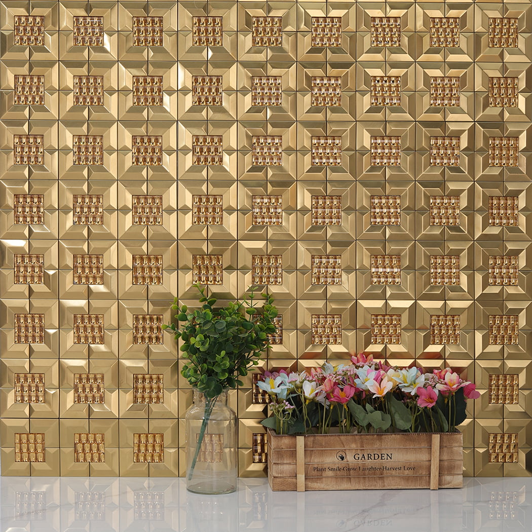 Gold 3D mirror metal mosaic tiles installed on a wall behind a bottle and flower box.