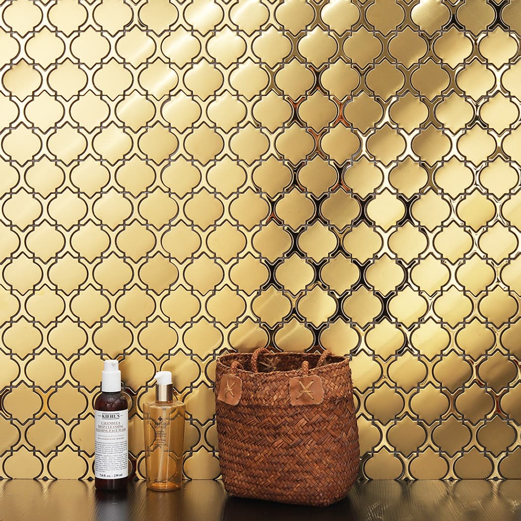 Gold lantern mosaic backsplash used as a backdrop for luxury bottles and decor.