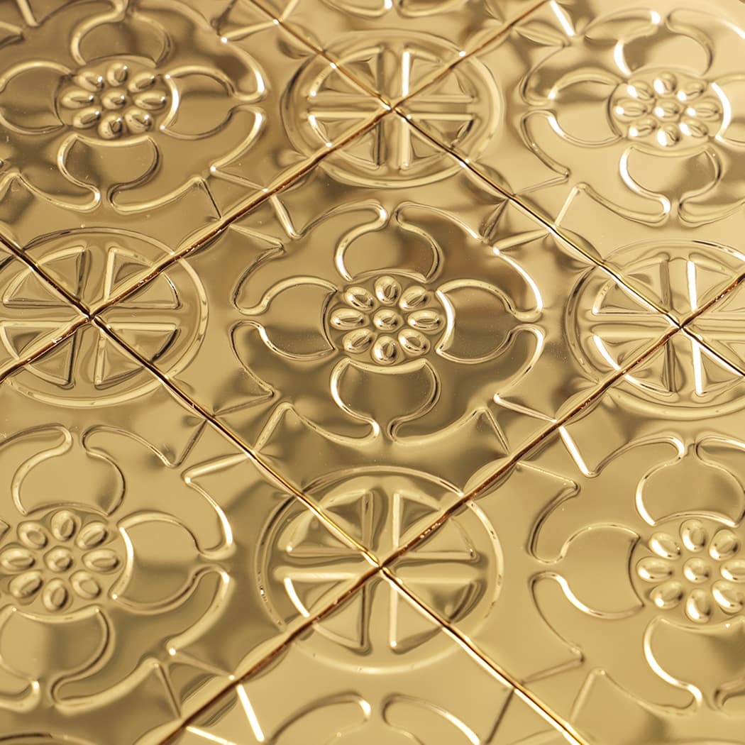 Close-up of gold embossed mosaic tiles with floral and circular geometric motifs.
