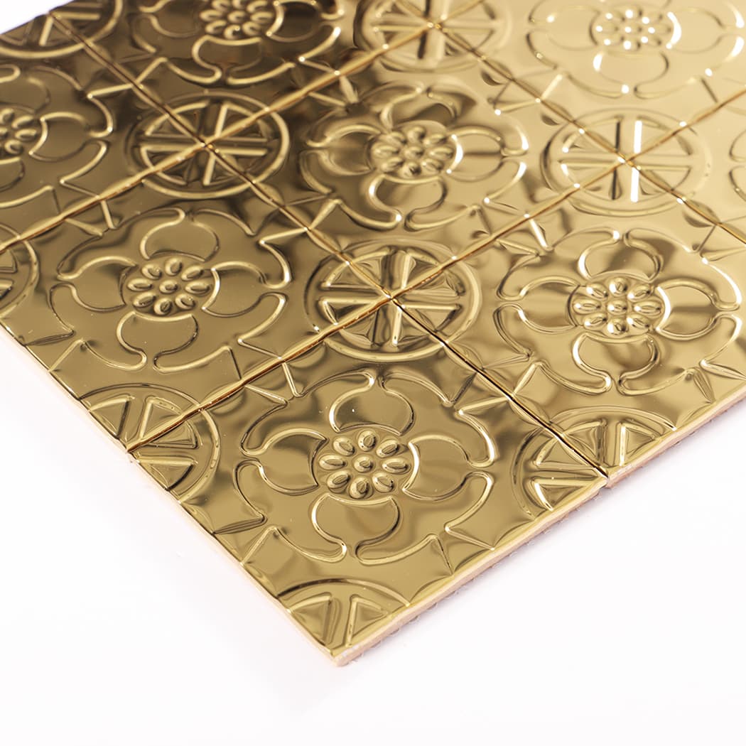 Angled view showing the edge and glossy embossed surface of gold mosaic tiles.