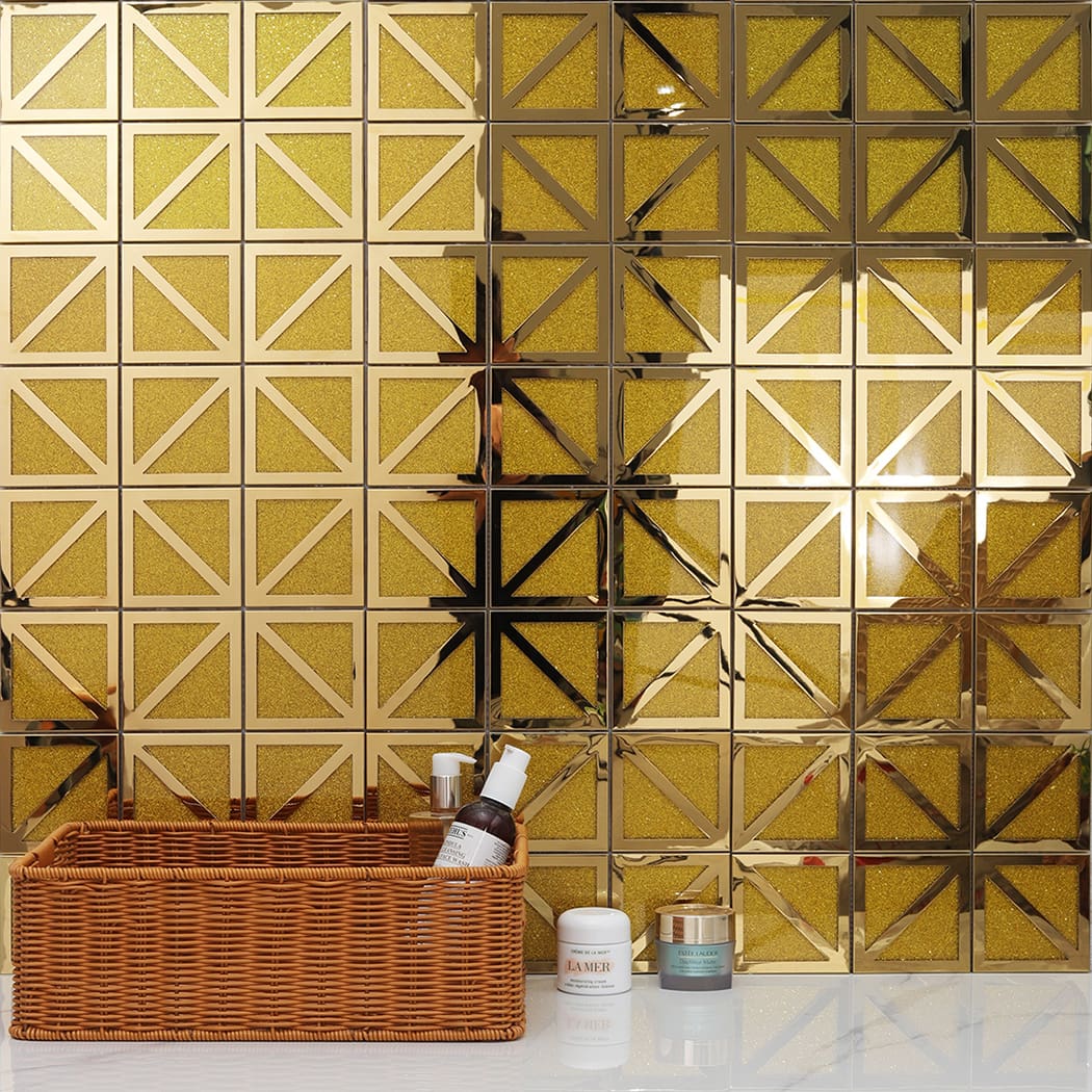 Luxury gold mosaic tile backsplash in a bathroom setting with decor and cosmetics.