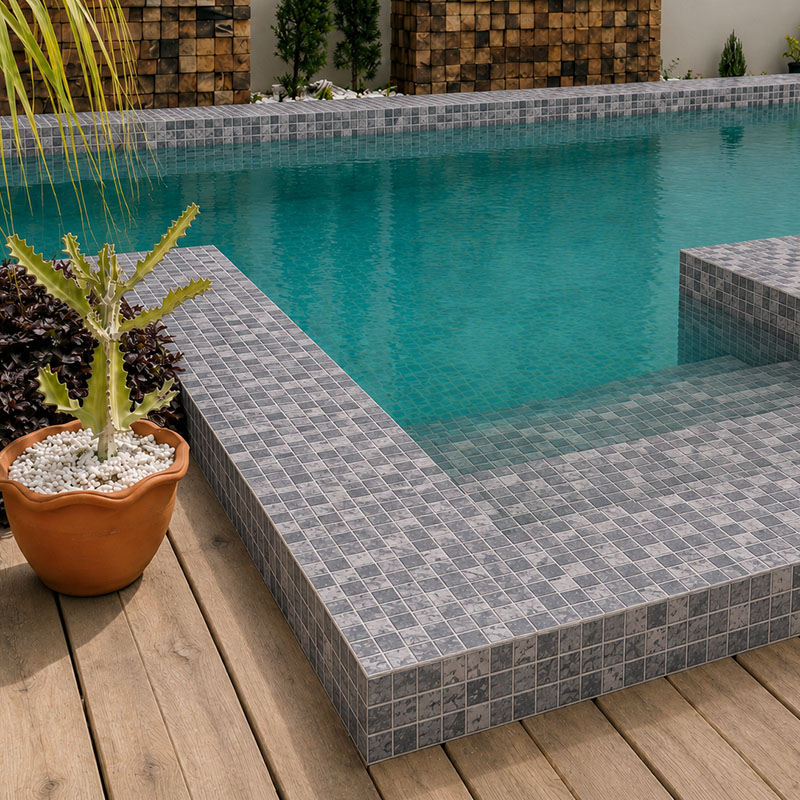 Gray mosaic poolside tiles installed around a turquoise pool with integrated steps