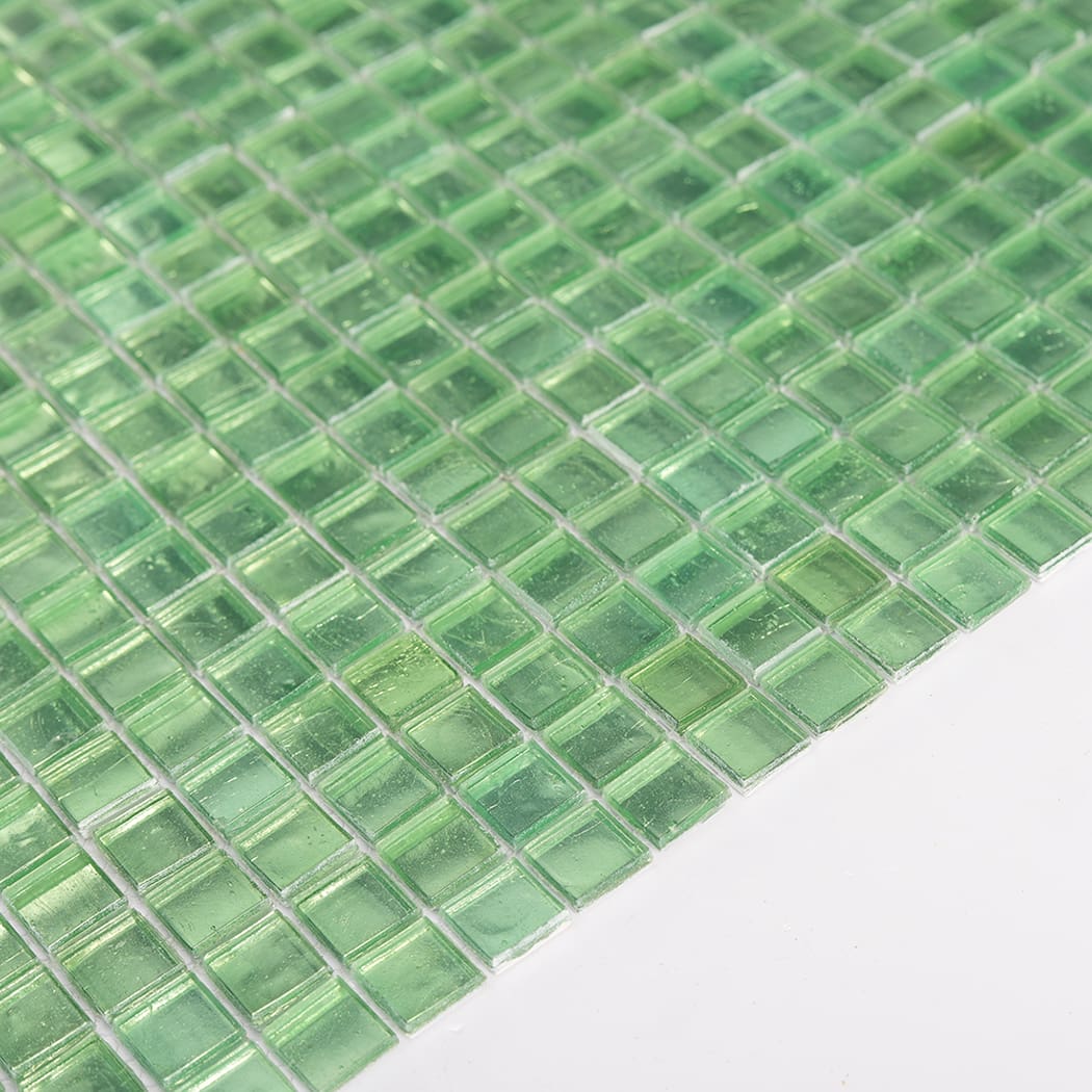 Angled view of green glass square mosaic tile sheet highlighting glass shine