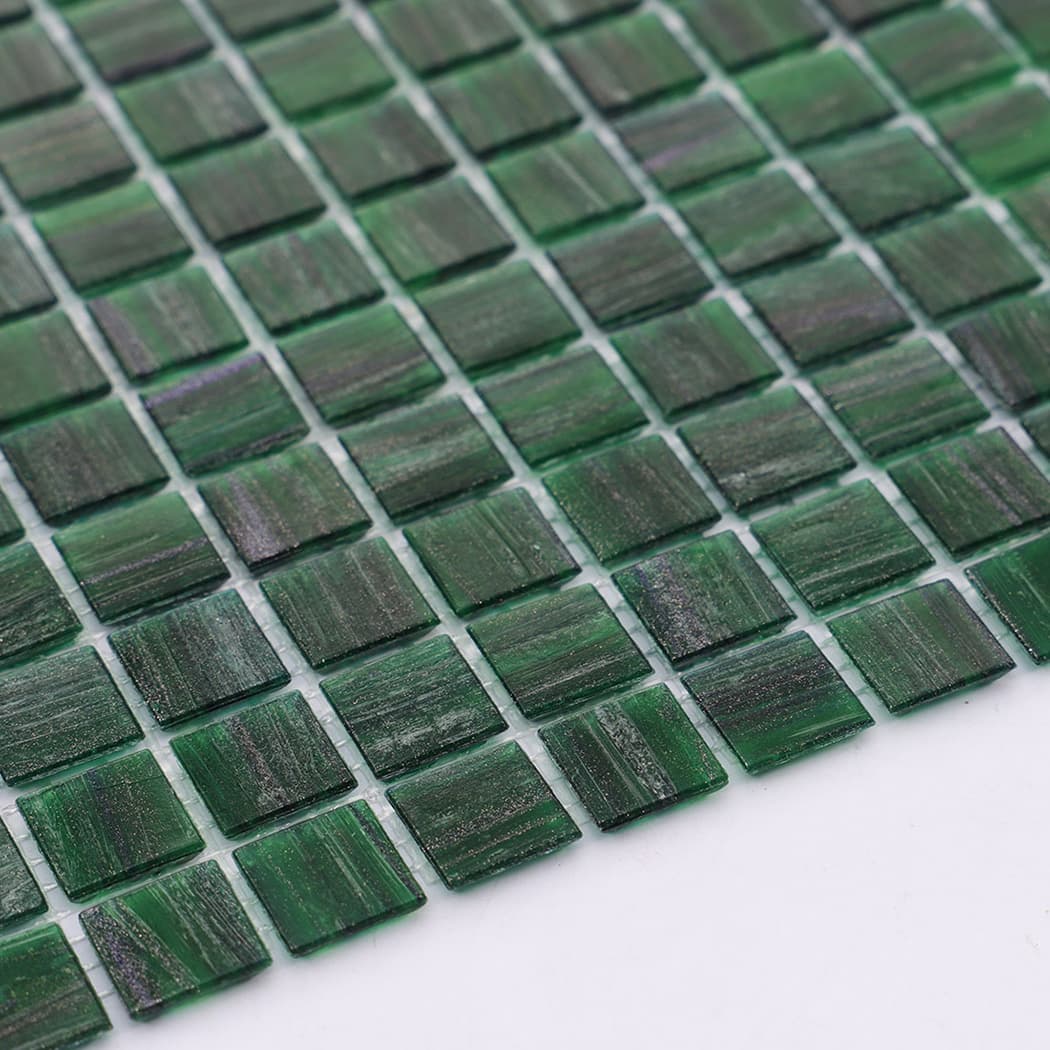 Side angle of green glass mosaic tile sheet showing texture and pattern