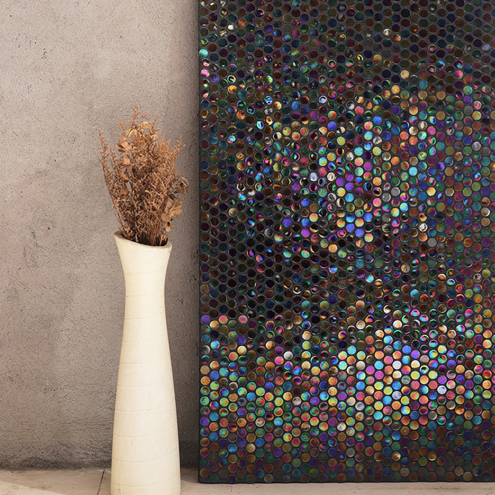 Penny Round iridescent mosaic tiles on the wall with a white vase beside them.