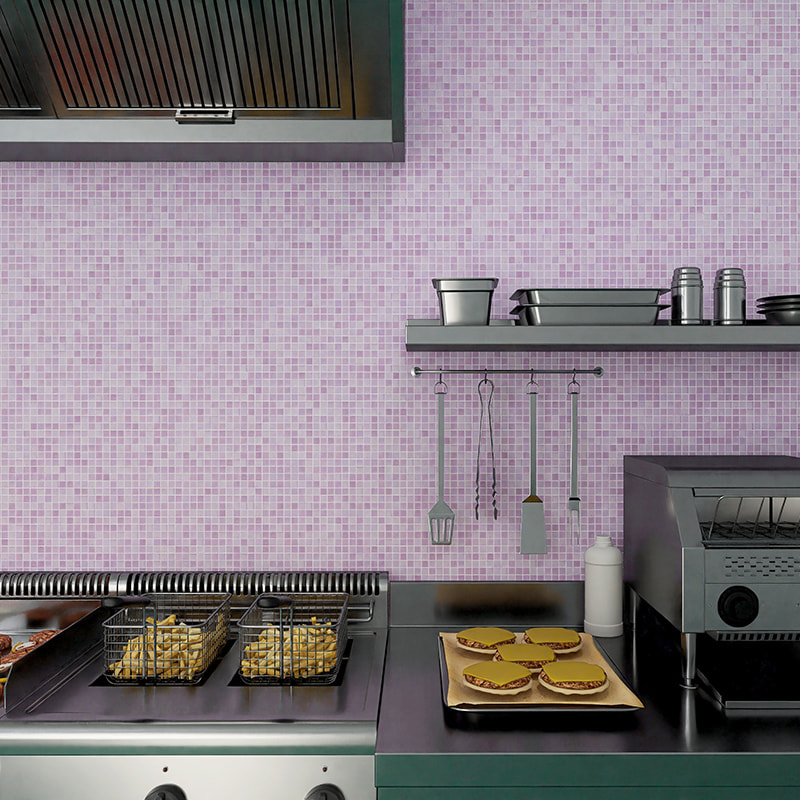 Commercial counter with fryer baskets of fries and utensils against a purple mosaic tile backsplash